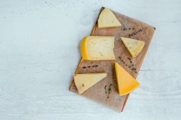 different fresh cheese on wooden cutting board. top view