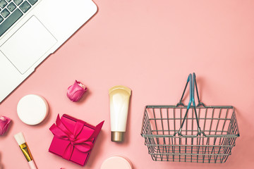 Concept of online shopping cosmetics. Top view on cosmetics bottles, cream, soap, makeup brushes, mobile phone on a pink background, flat lay, frame