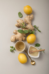 Wall Mural - Ginger Lemon Tea with Honey. Warming immune boosting tea with citrus and ginger. Cup, honey,  ginger root on grey  pastel background, copy space, top view.