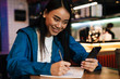 © Drobot Dean - Photo of asian woman making notes and using cellphone