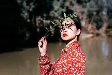 Beautiful Asian Lady With Closed Eyes And Shadow Of Plant Twig On Face Standing Against Lake In Countryside
