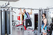 © Luis Manuel Matias/ADDICTIVE STOCK - Low angle of pensive instructor watching determined athlete in sportswear performing pull ups exercise on bar in contemporary sport club