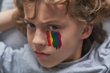 Unhappy Boy With Rainbow Under Eye Looking At Camera At Home During Quarantine