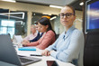 © AnnaStills - Portrait of young businesswoman in eyeglasses looking at camera while sitting at the table at meeting with her colleagues in the background
