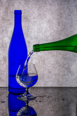 Pouring liquid from a green bottle into a glass