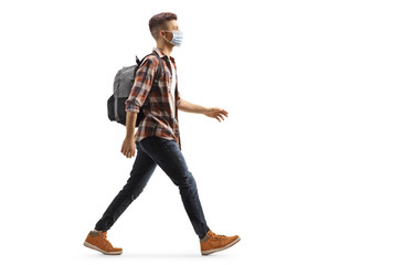 Wall Mural - Young guy with a backpack wearing a protective medical mask and walking
