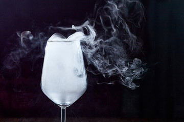 In a wine glass, developing smoke. On a black background