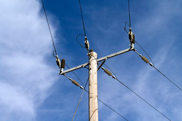 Electric post with wires in front of blue sky 