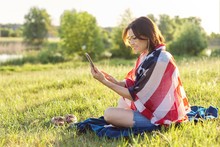 Adult Woman Sitting On July Evening In Nature With USA Flag Scarf