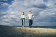© Daria - Happy young couple having fun at beach on sunny evening. Smiling teens on vacation. Laughing couple in love holding hand enjoying summertime. Guy leading his girlfriend