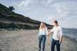 © Daria - Happy young couple having fun at beach on sunny evening. Smiling teens on vacation. Laughing couple in love holding hand enjoying summertime. Guy leading his girlfriend