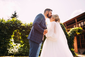 Wall Mural - Beautiful wedding couple in a luxurious place for a photo shoot with flowers and architecture, the bride and groom in an embrace and love, the newlyweds are happy