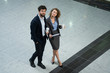 © Ivan - Business man and woman standing in the middle of the hall, drinking coffee and reading the document