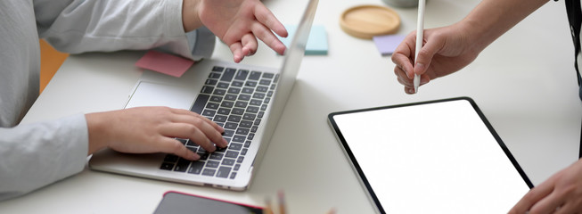 Cropped shot of two businesswoman working together on white table