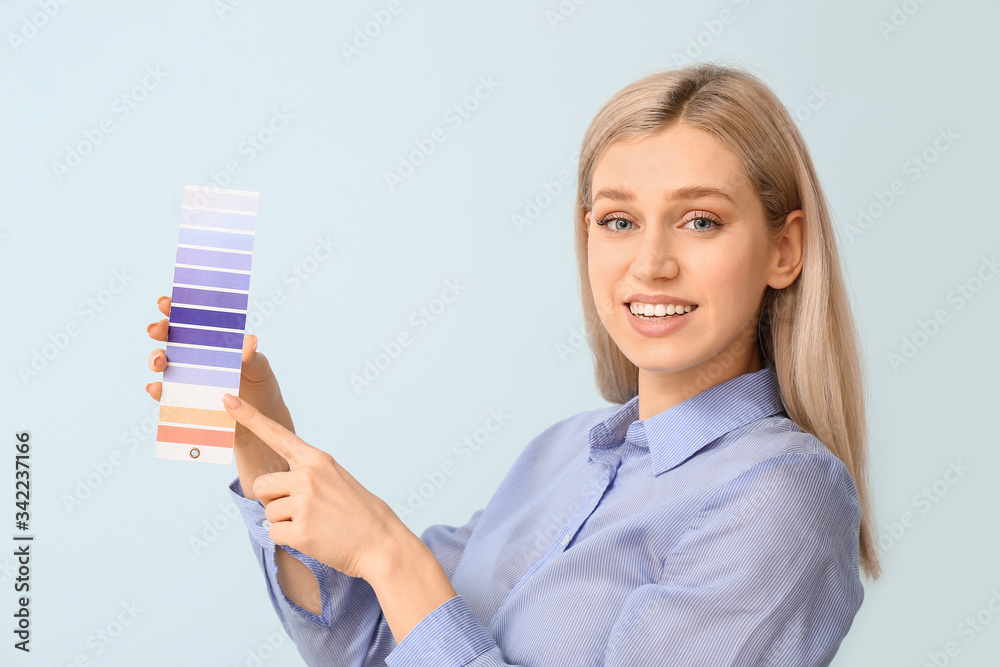 Young woman with paint palette on color background
