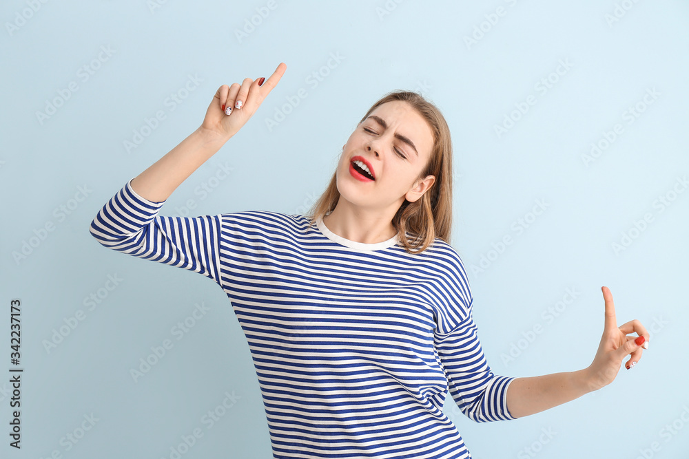 Dancing young woman on color background