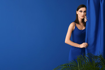 Poster - Portrait of fashionable young woman with fabric on blue background