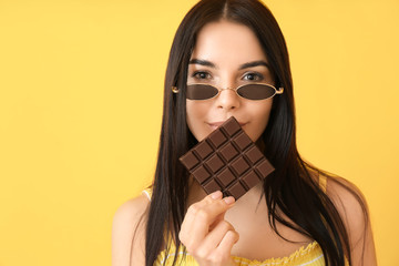 Wall Mural - Beautiful young woman with tasty chocolate on color background