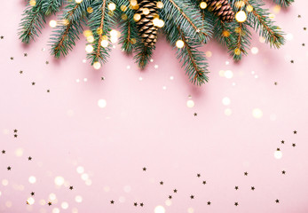 Christmas natural coniferous border with cones and confetti. Festive pink background with sparkles and bokeh lights