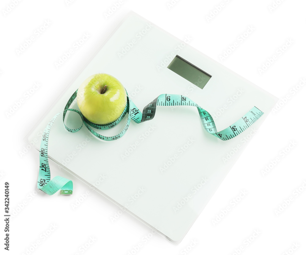 Weight scales with measuring tape and apple on white background. Slimming concept