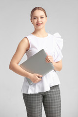 Sticker - Portrait of young businesswoman with laptop on grey background