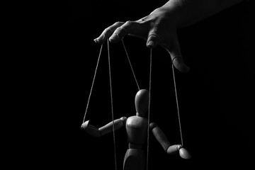 Conceptual image of a hand with strings to control a marionette in monochrome