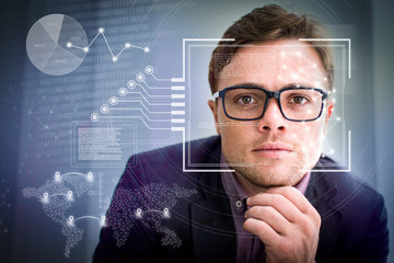 Businessman in eyeglasses and virtual identification graphics. Serious face of young Caucasian man wearing suit, looking at camera and touching chin