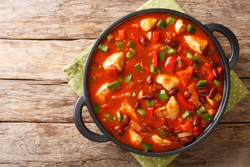 Wall Mural - Thick tasty chicken stew with red beans in spicy chili sauce close-up in a pan. horizontall top view