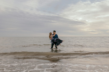 strong man with his feet in the water carrying his girl