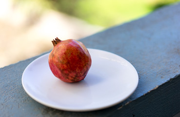 Wall Mural - Fresh raw ripe pomegranate on a white plate, close up view, fruit, background