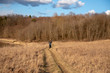 © FO_DE - A man rides a Bicycle on dry grass against a background of bare trees.
