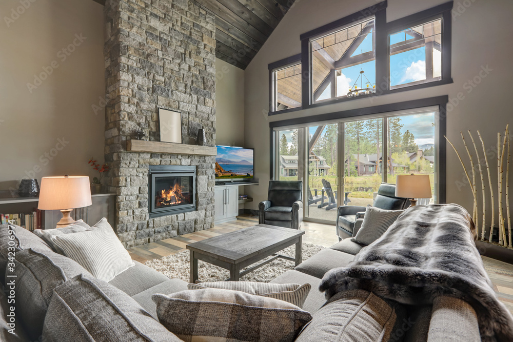 Living room luxury interior with large stone fireplace and leather furniture and huge tall windows with natural tones. - obrazy, fototapety, plakaty 