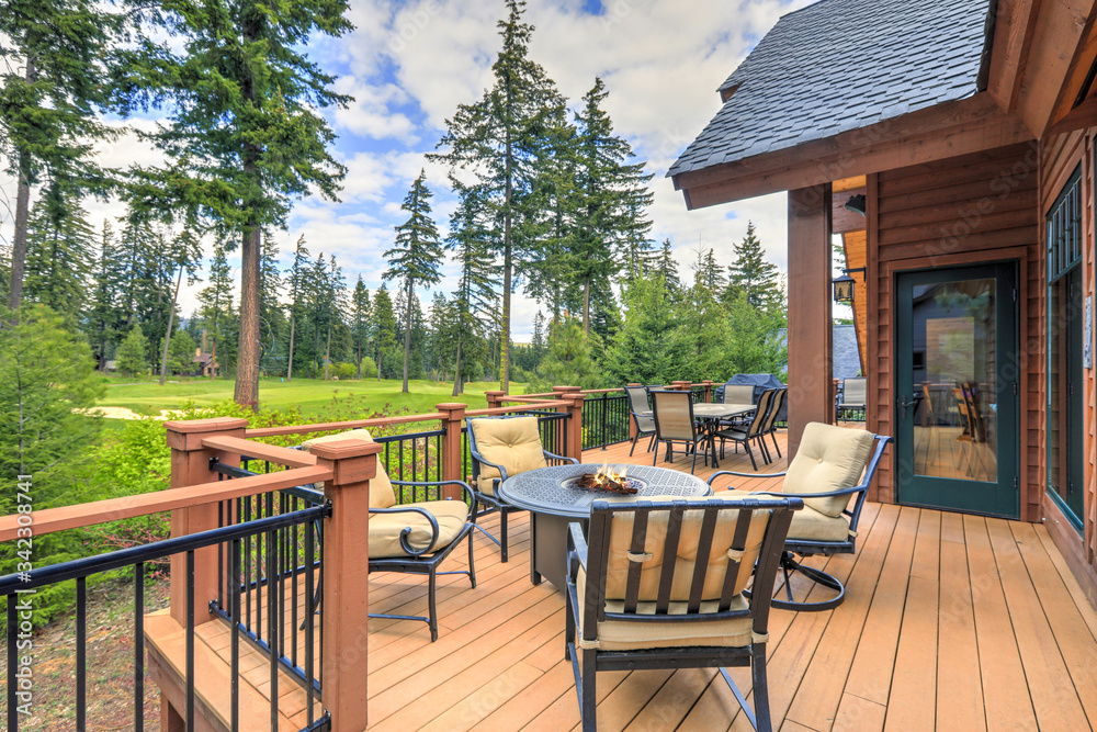 Beautiful large cabin home  with large wooden deck and chairs with table overlooking golf course. - obrazy, fototapety, plakaty 