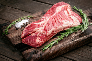 Canvas Print - Raw hanging tender or onglet steak of beef on wooden Board with rosemary and thyme on wooden background