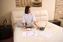 Young  woman businessman on self-isolation during a coronovirus pandemic COVID-19 on self-isolation works at home, sits on bed, checks mail, does his work remotely, telework