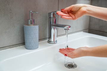 Wall Mural - White sink with a silver faucet in the bathroom. Gray can with liquid soap for hands. Turning on the tap water, personal hand hygiene. Hand washing under running water