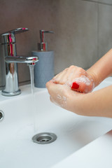 Wall Mural - White sink with a silver faucet in the bathroom. Gray can with liquid soap for hands. Turning on the tap water, personal hand hygiene. Hand washing under running water