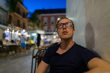 Wall Mural - Young handsome tourist man with eyeglasses thinking outdoors