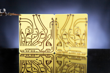 Close up of two raw print circuit boards pcb supported by third hand. Black background