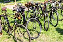 Many Old Rusty Vintage Retro German Military Bicyles Stand In Row On Open Air Parking At City Park. World War 2 Bike Transport Exhibition Or Flea Market On Sunny Day Outdoors