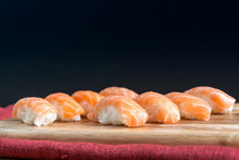 Close-up Of Fresh Salmon Sushi Served On Wooden Tray Against Black Background