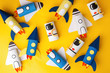 School kindergarten crafts, paper spaceship, shuttle, astronaut on yellow background with copy space for text. Party, start up launch concept, diy, creative idea from toilet tube, recycle