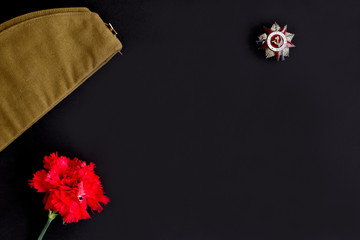 Forage,garisson cap of World War II soldier with red star,carnation flower,order,medal.Memory of 75 years of victory day on May 9 of the Soviet Union in Great Patriotic War.Dark background.Copy space