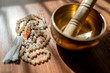 Handmade sacred mala seed beads and a golden Tibetan bowl on a wooden background in the soft and beautiful light of morning, a perfect time for a yoga session acompanied by healing sounds.