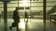 © helivideo - SILHOUETTE Unrecognizable tourists hurry up and down Frankfurt airport at sunset