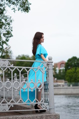 Beautiful girl in a blue long dress posing in a meadow in various elegant poses. Professional model with long hair