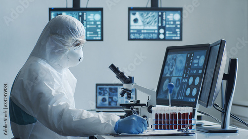 Fotomural Scientist in protection suit and masks working in research lab using laboratory equipment: microscopes, test tubes