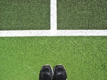 Low Section Of Person Standing On Playing Field