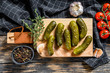 Marinated cucumbers gherkins on wooden cutting board. Pickles with mustard and garlic. Black background. Top view