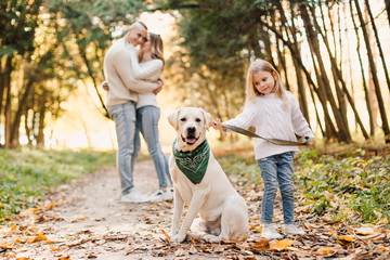 Happy beautiful family with dog labrador is having fun together walking the in park.